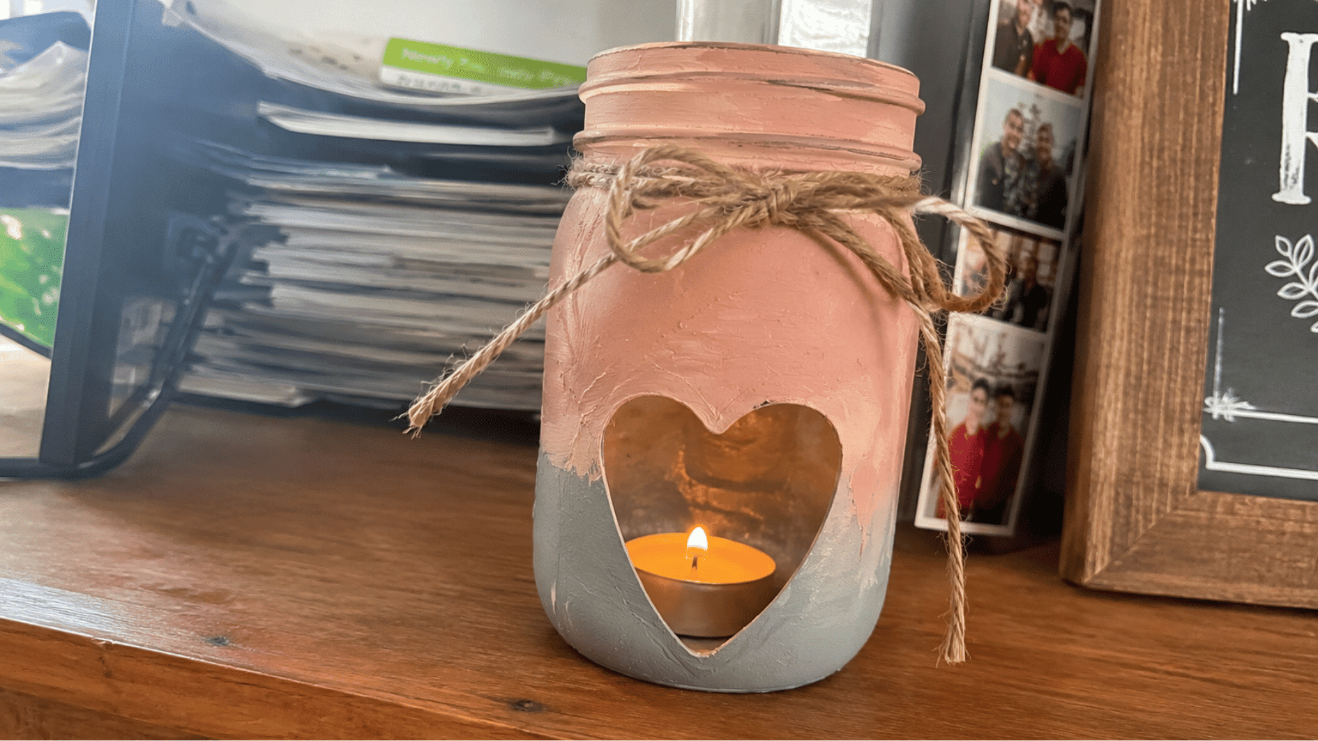 Painted mason jar candle holder with twine and glowing tea light.