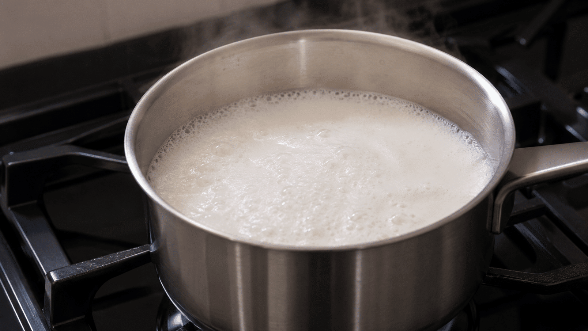 boiling milk in a steel pot on a gas stove stem rising in a modern kitchen setting visible hot stem rising from the milk