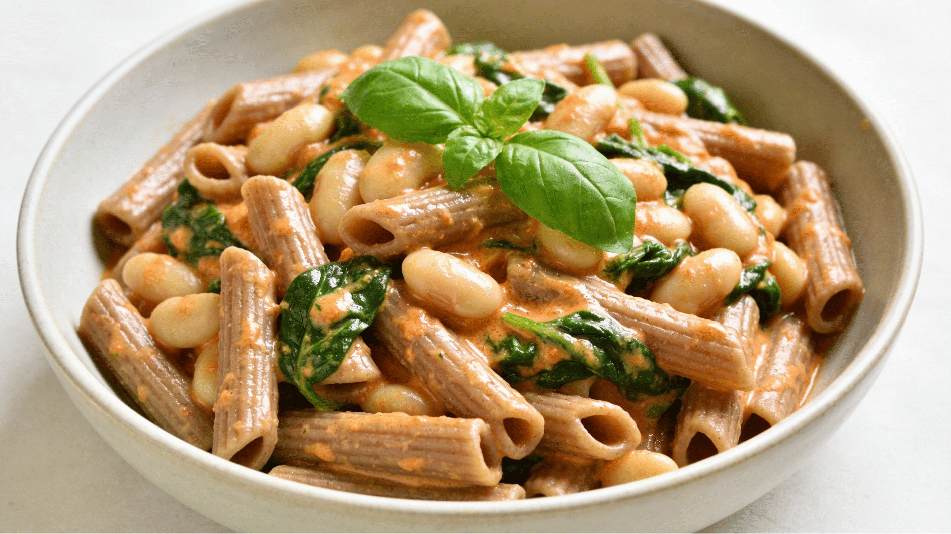 creamy tuscan white bean pasta with spinach basil tomatoes and whole wheat pasta in a comforting bowl