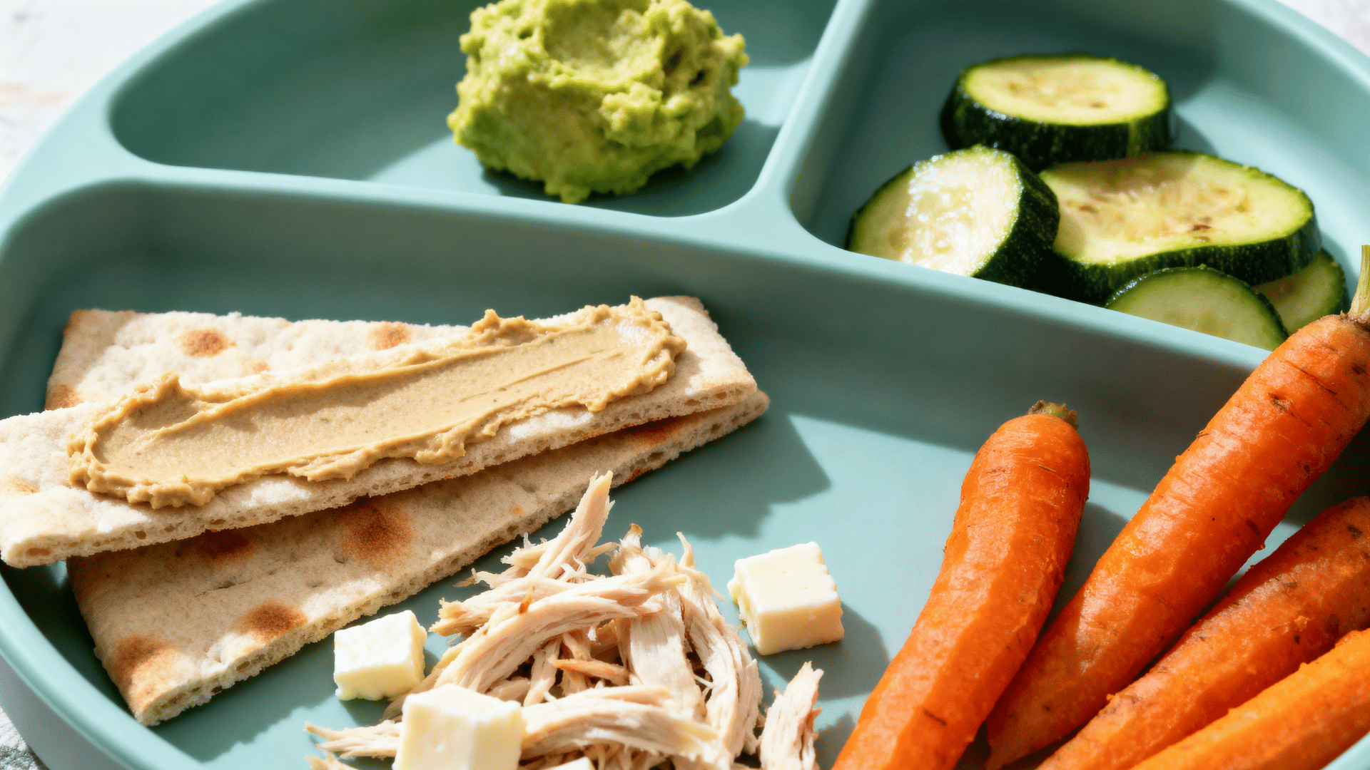 hummus and soft pita plate with chicken carrots zucchini and avocado