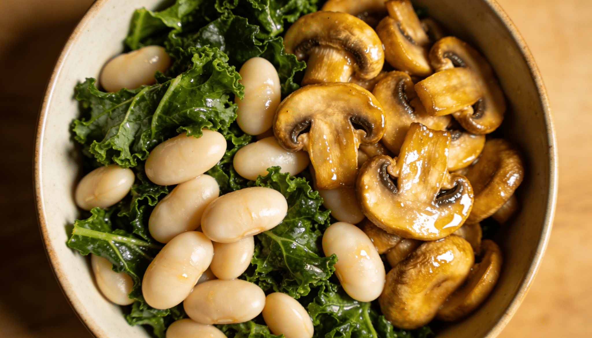 kale and white bean breakfast bowl with sauteed mushrooms white beans and fresh kale in a ceramic bowl on wooden surface