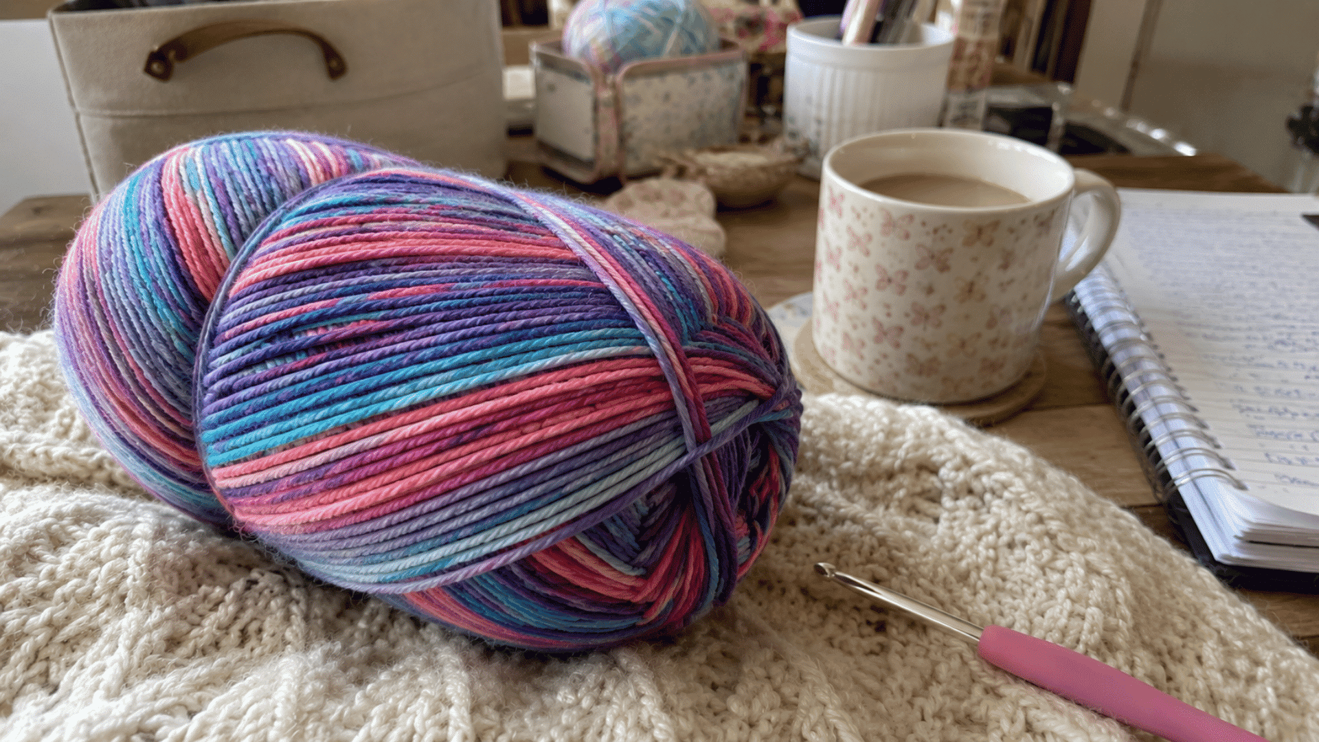 multicolor self-striping yarn skein with a crochet hook on a wooden craft table