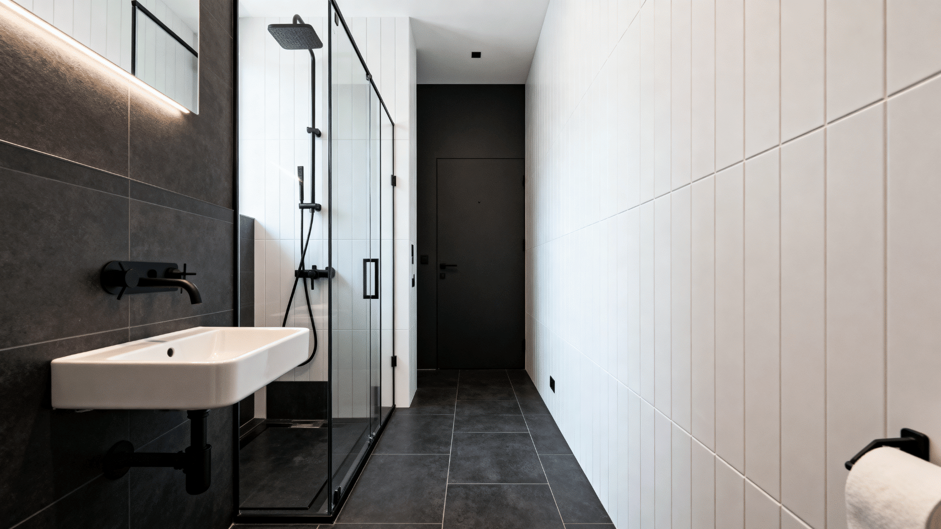 narrow bathroom with fixed glass shower screen and black fixtures