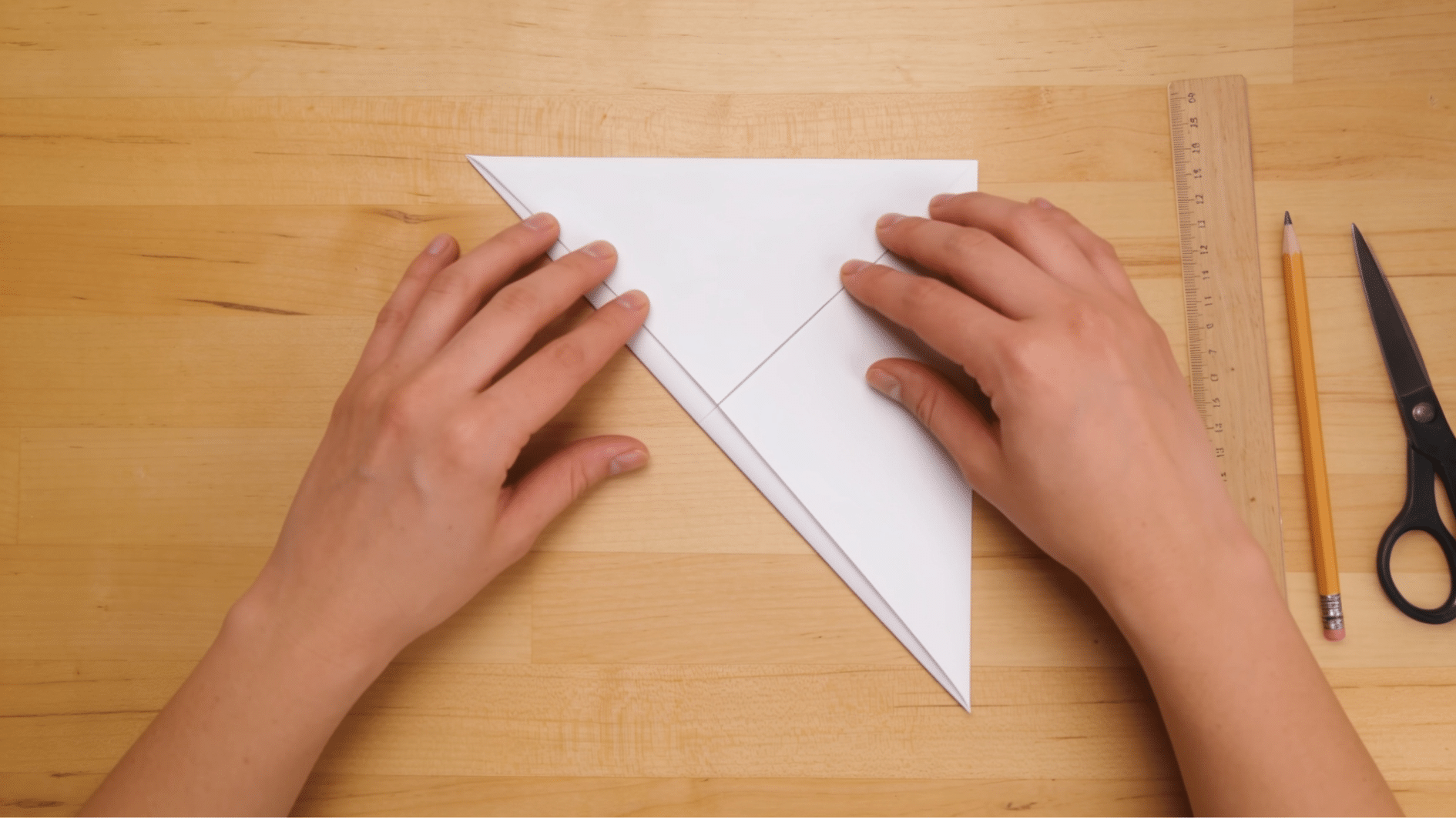 paper folded diagonally into a triangle with aligned corners on a wooden craft table