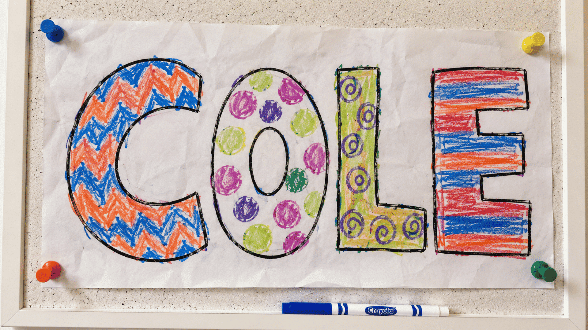 pattern filled name art with zigzags dots swirls and stripes pinned to cork board
