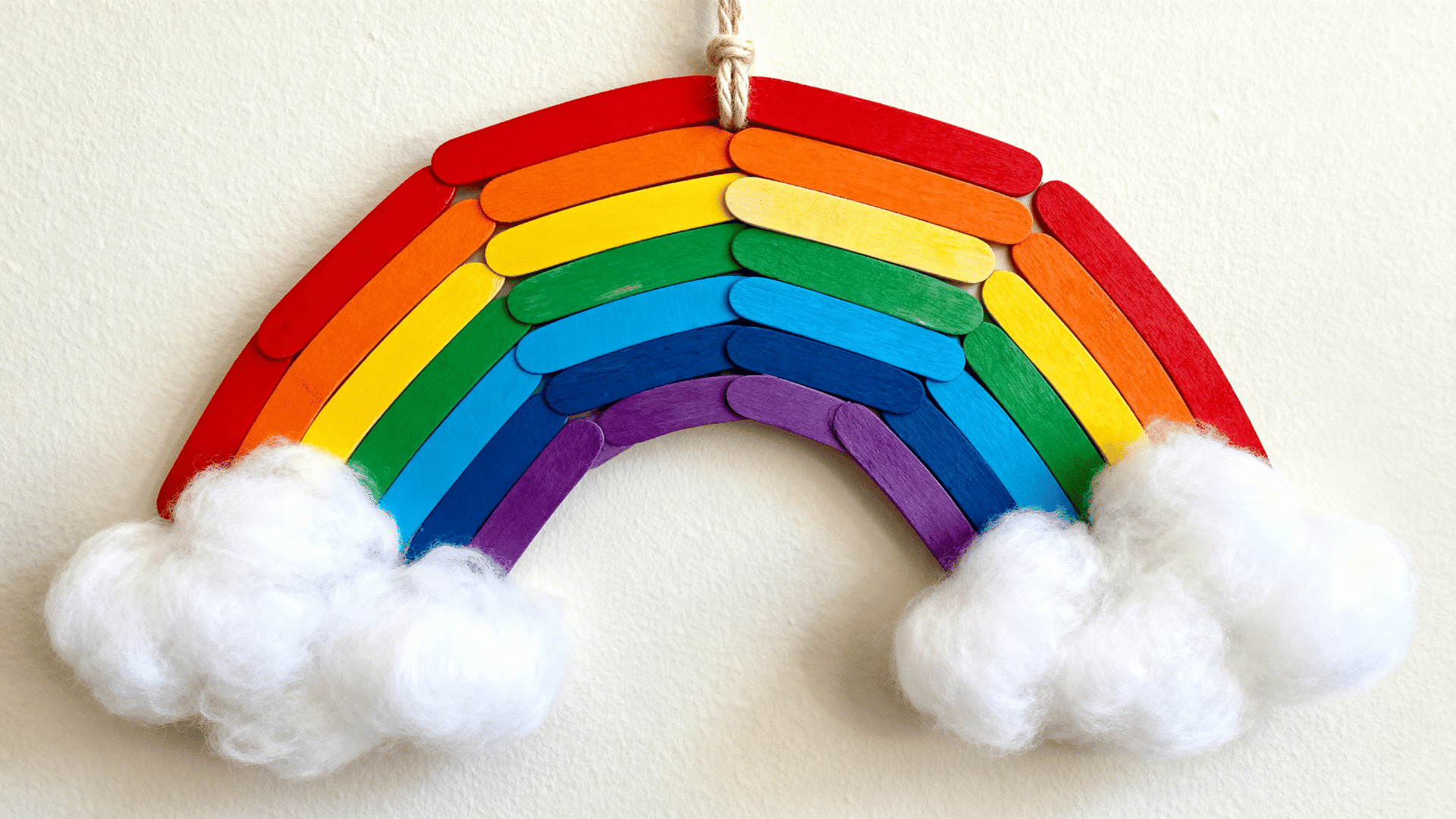 popsicle stick rainbow wall hanging with cotton clouds and yarn loop