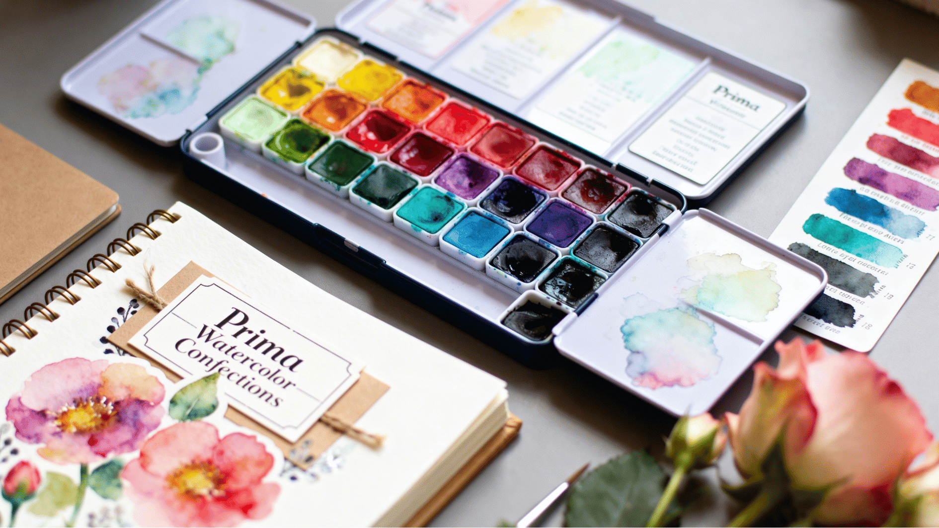 prima watercolor confections set with themed pans, journal pages, floral sketches and soft creative craft painting setup