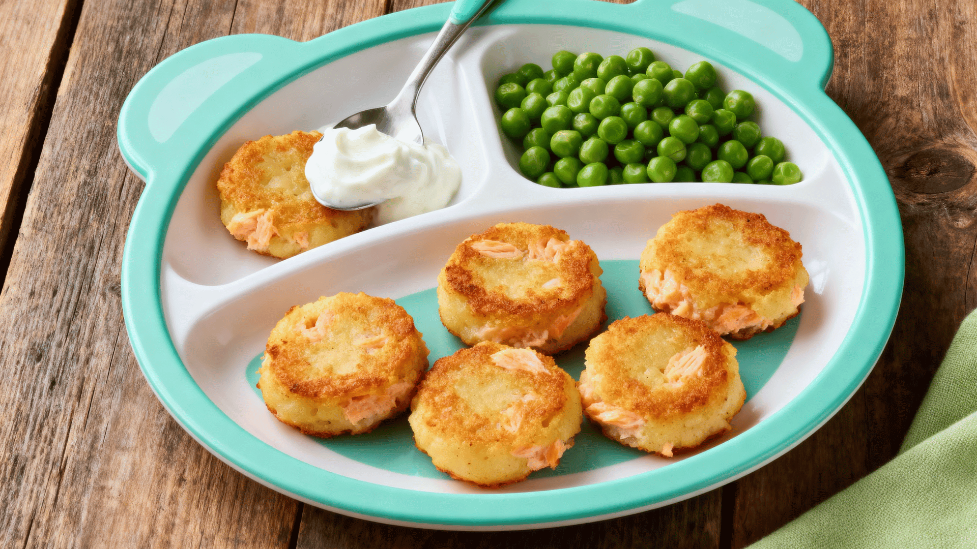 salmon potato patties with yogurt dip and peas on a toddler plate
