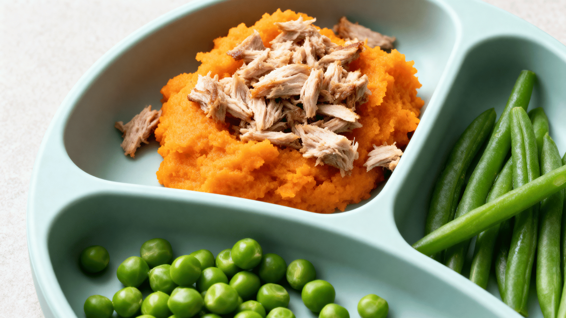 turkey and sweet potato bites with peas on a small toddler meal plate