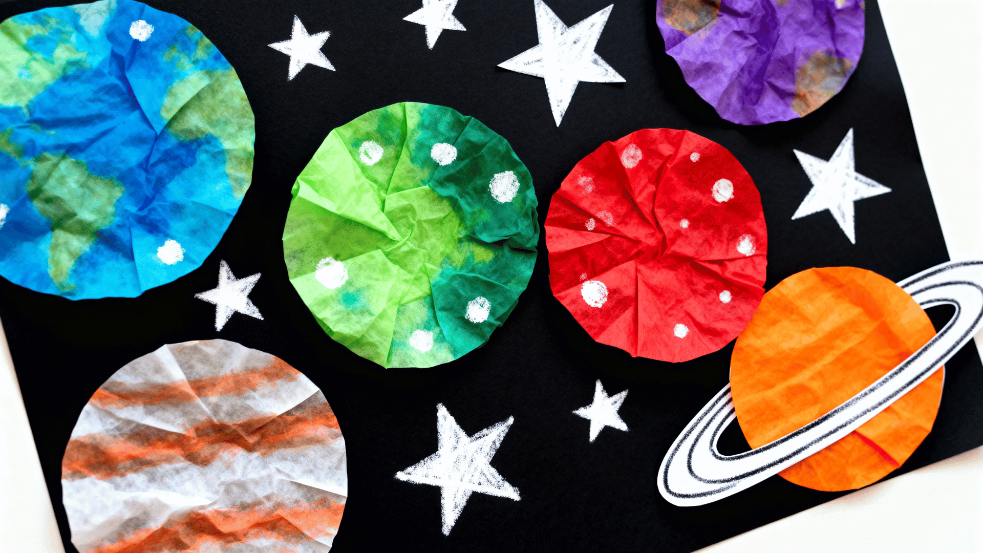 coffee filter planets on black construction paper with paper stars, markers, glue, and a simple saturn ring nearby