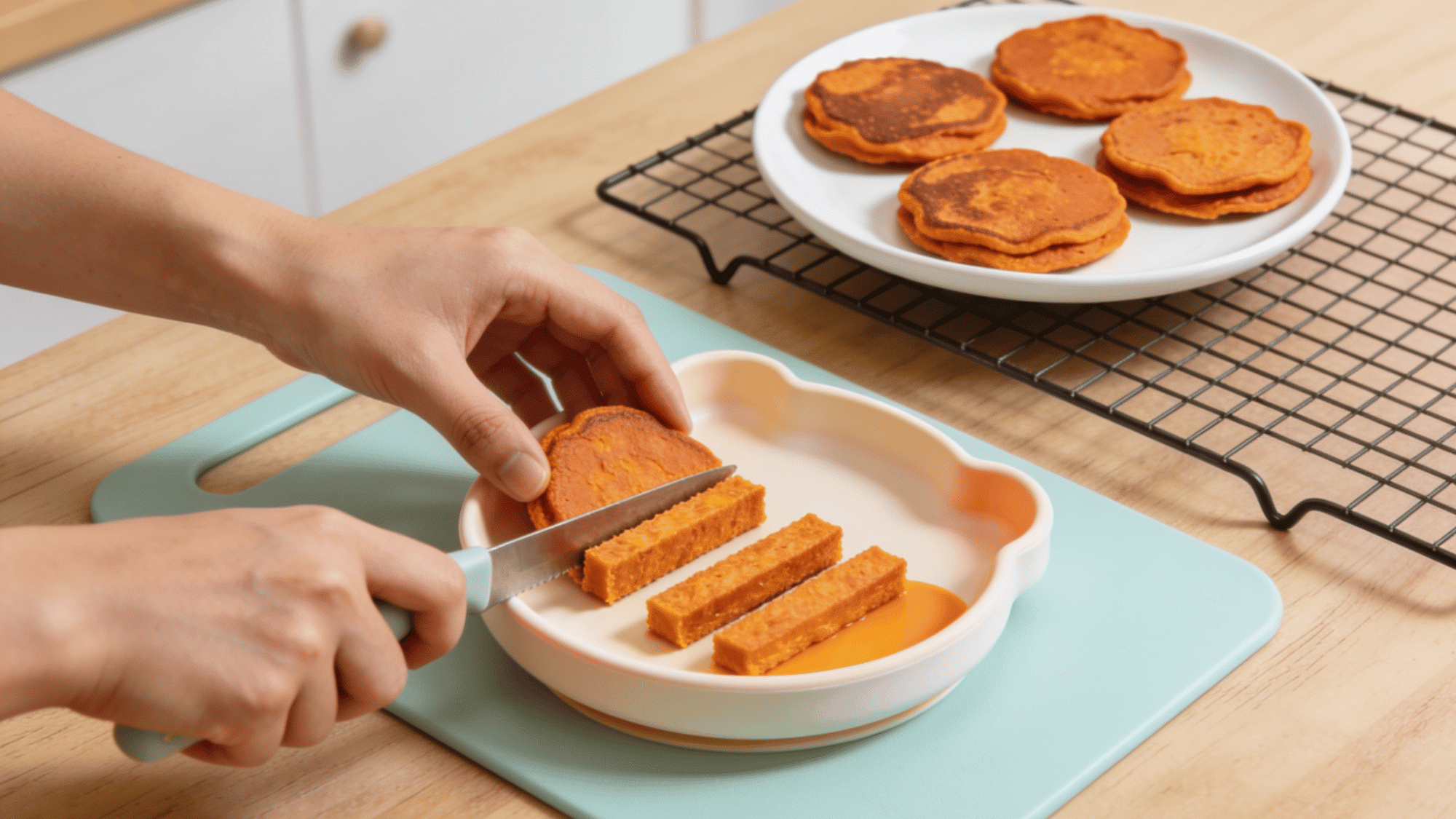 cutting soft sweet potato pancakes into finger-sized strips for easy baby-led weaning meals.