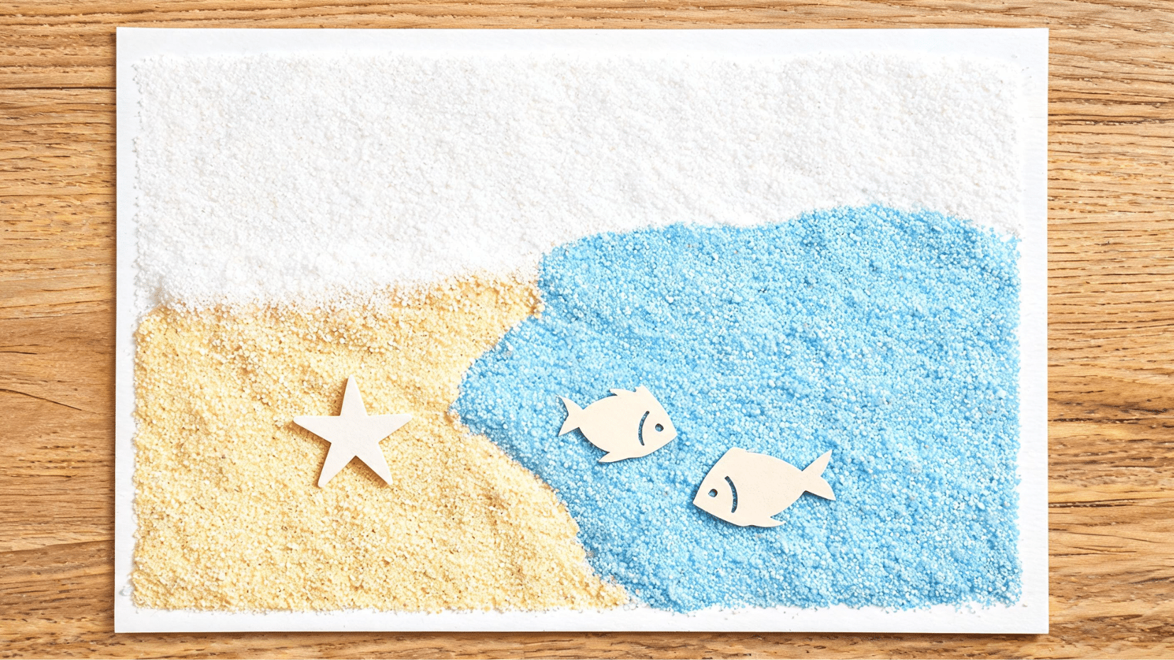 handmade paper craft fish and star shapes on blue sand (1)