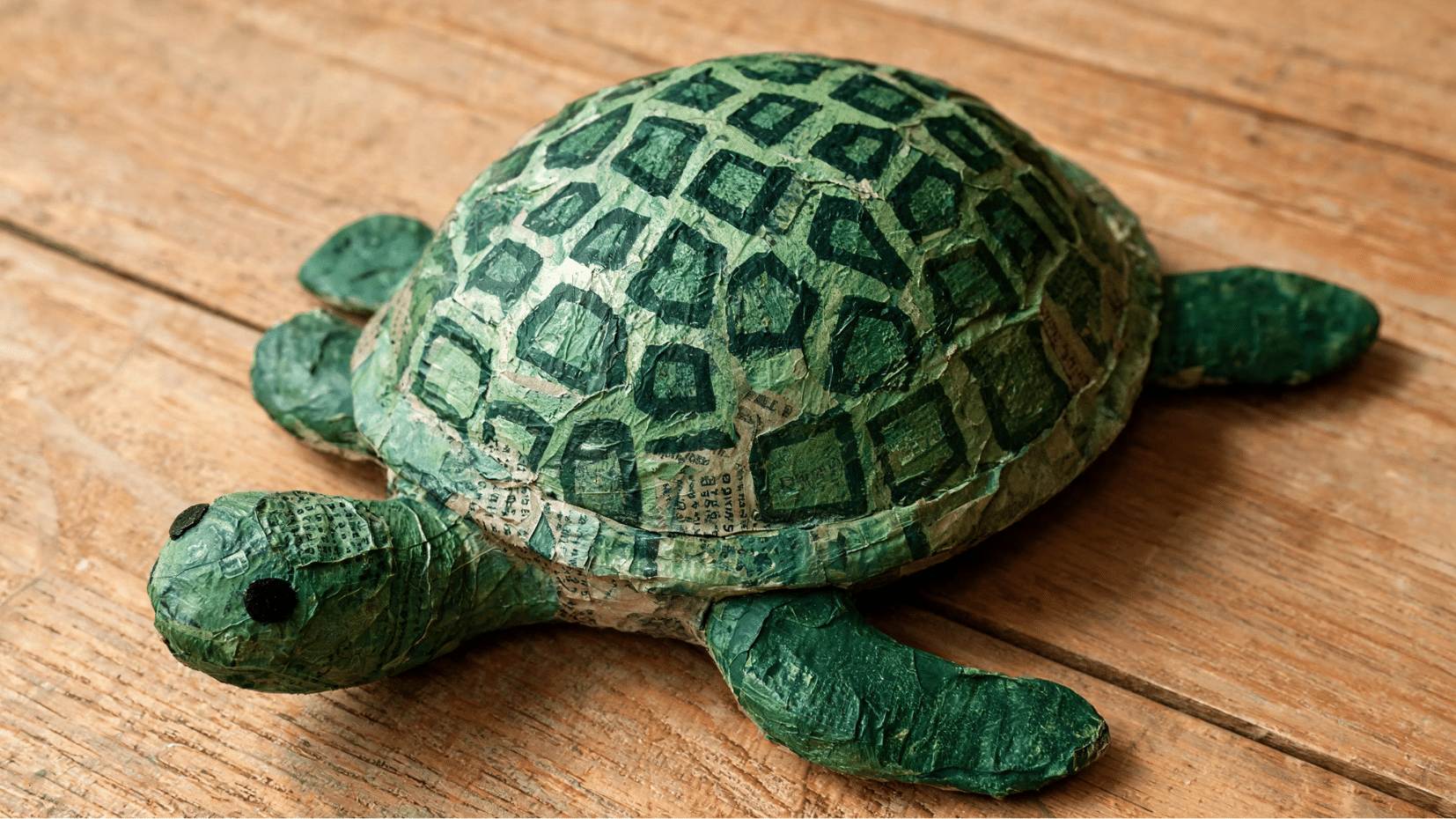 handmade turtle craft made from painted paper and newspaper pieces on a wooden surface (1)