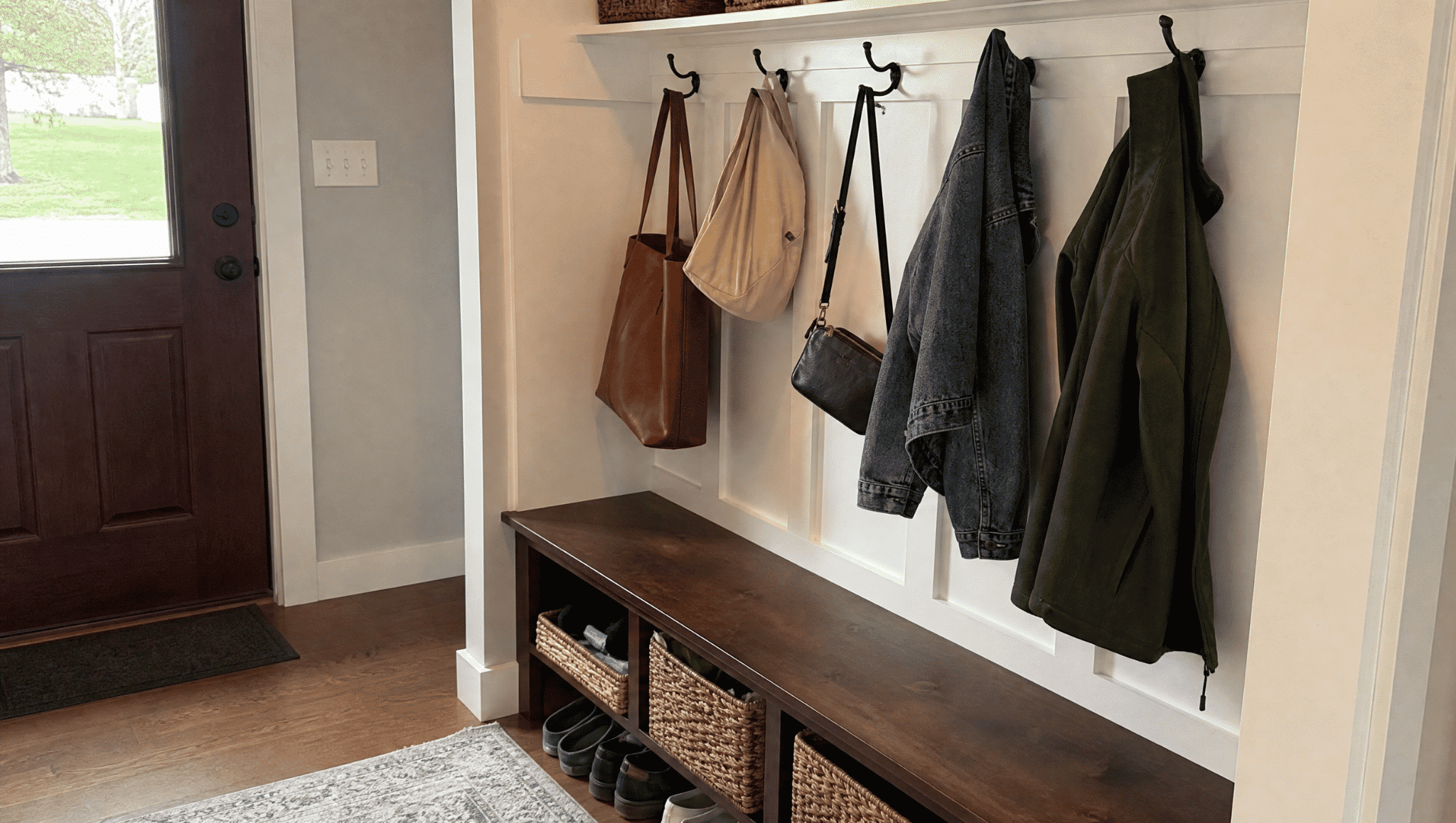 organized entryway with bench and hooks showing a simple home renovation idea for better storage