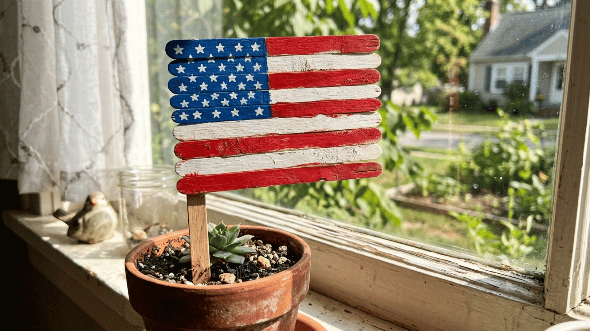 popsicle stick american flag craft displayed in a flower pot on a sunny windowsill