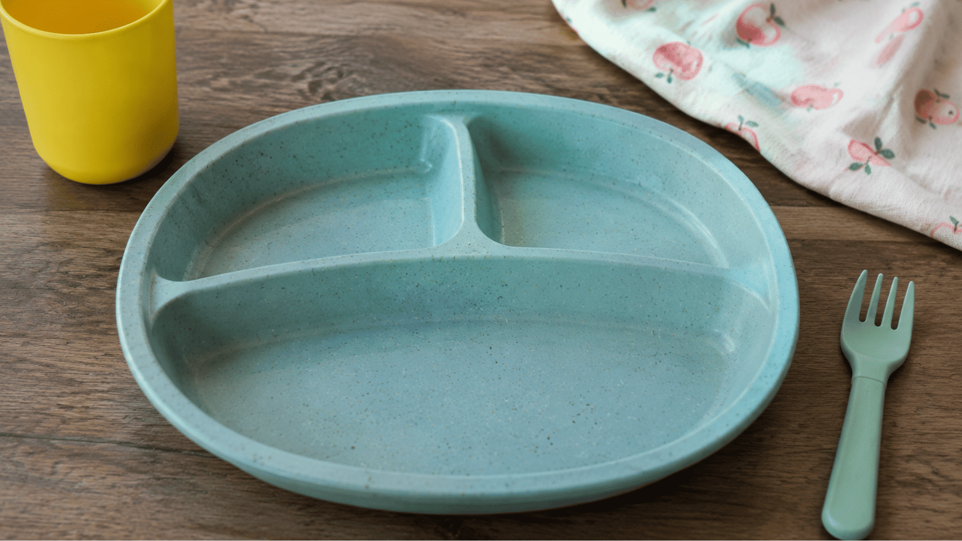 **Alt Text:** recycled plastic kids plate with divided sections and matte finish placed on a wooden table in a simple setup