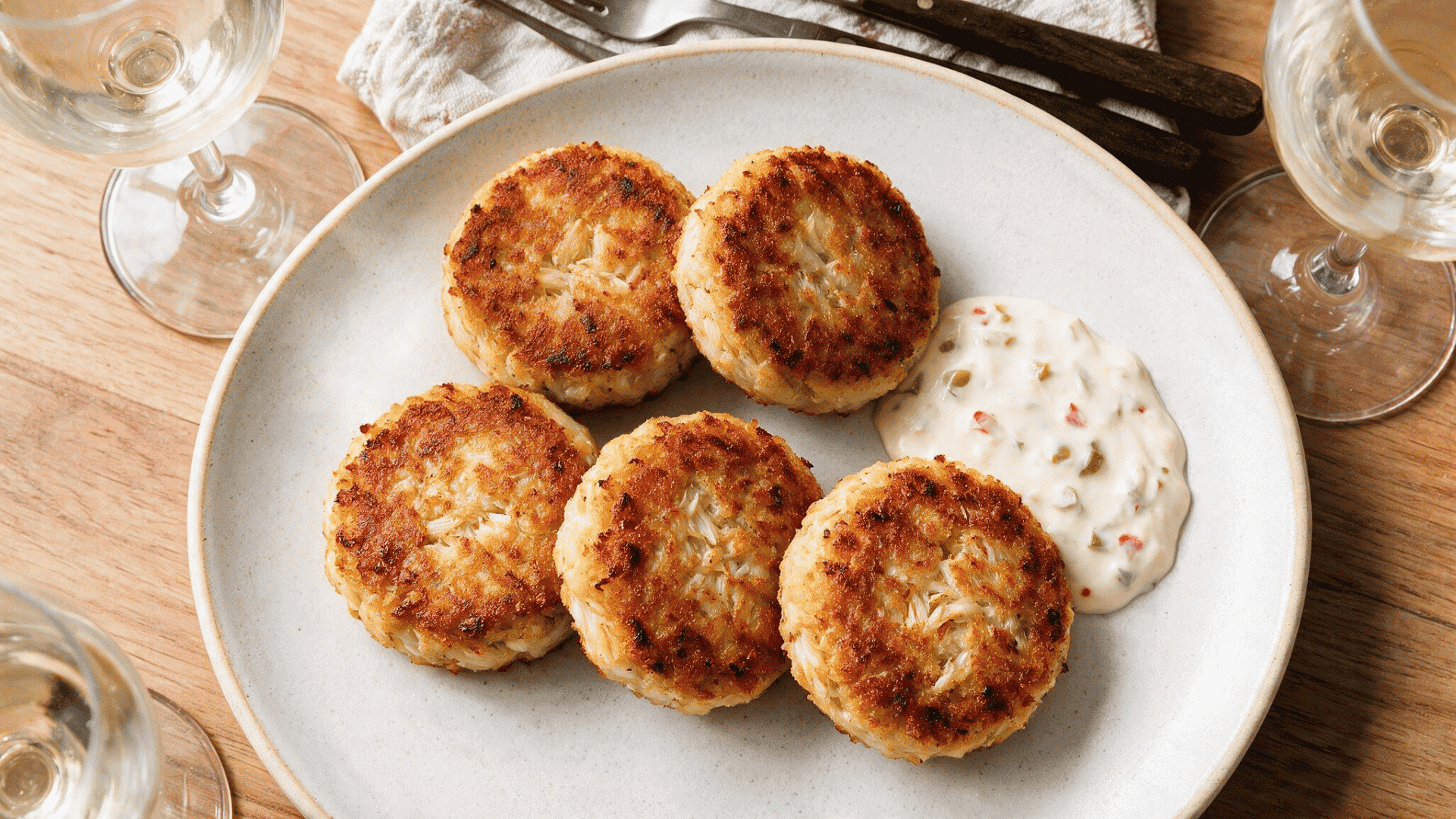 Crispy crab cakes with lemon and tartar sauce on a blue plate