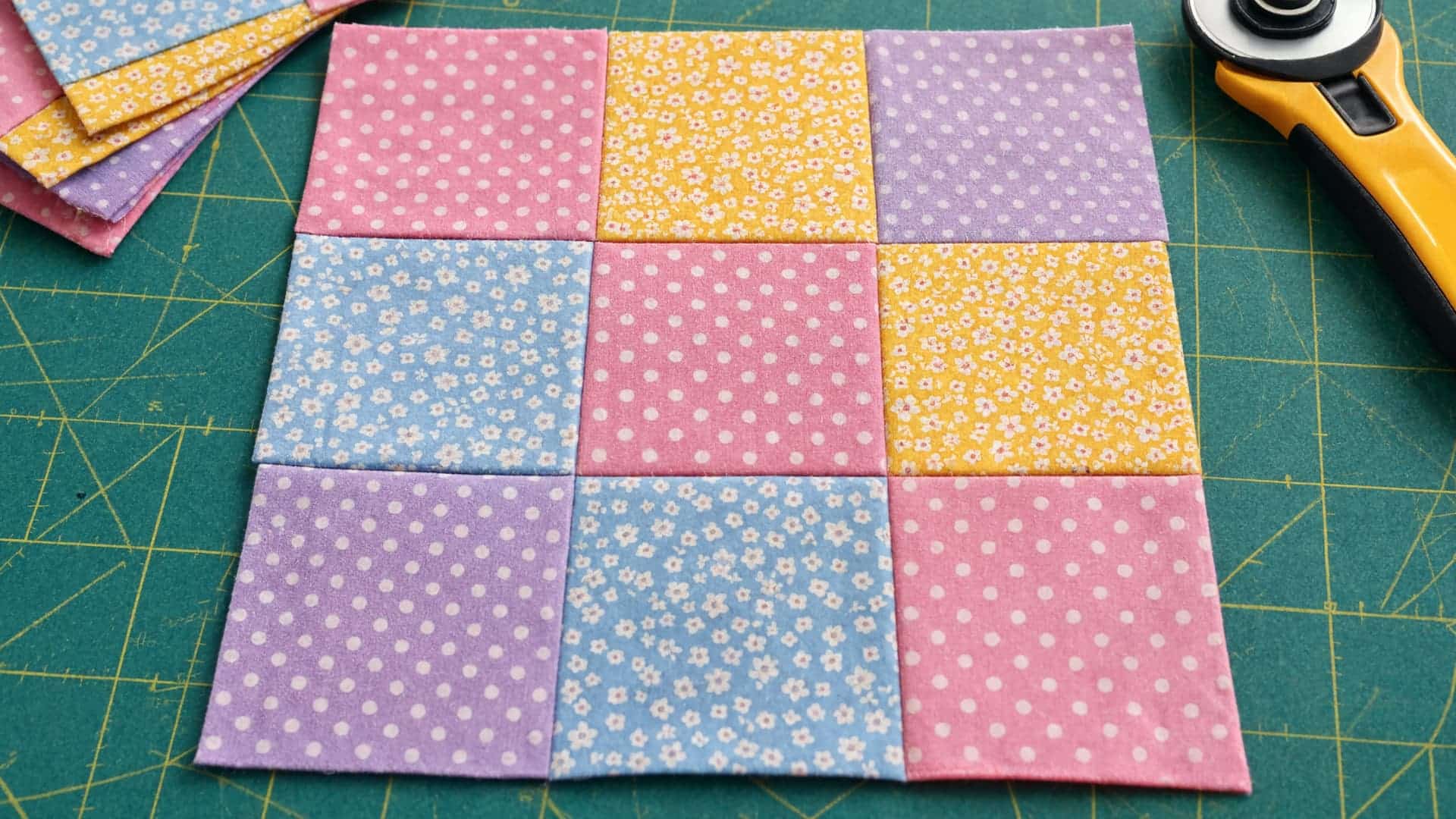nine patch quilt block with pastel fabric squares arranged in a neat checkerboard pattern