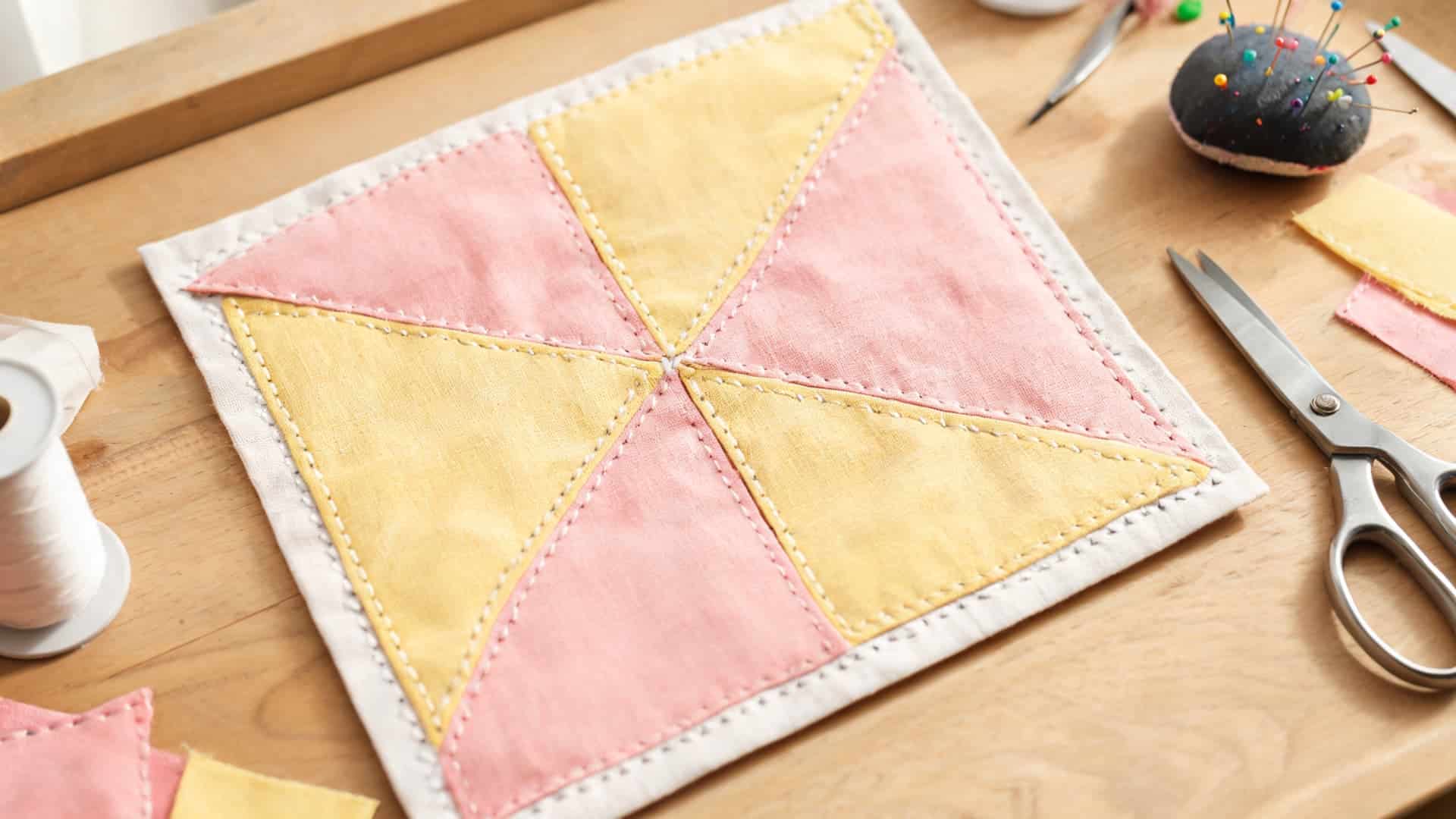 pinwheel quilt block with rotating fabric triangles and neat center stitching details