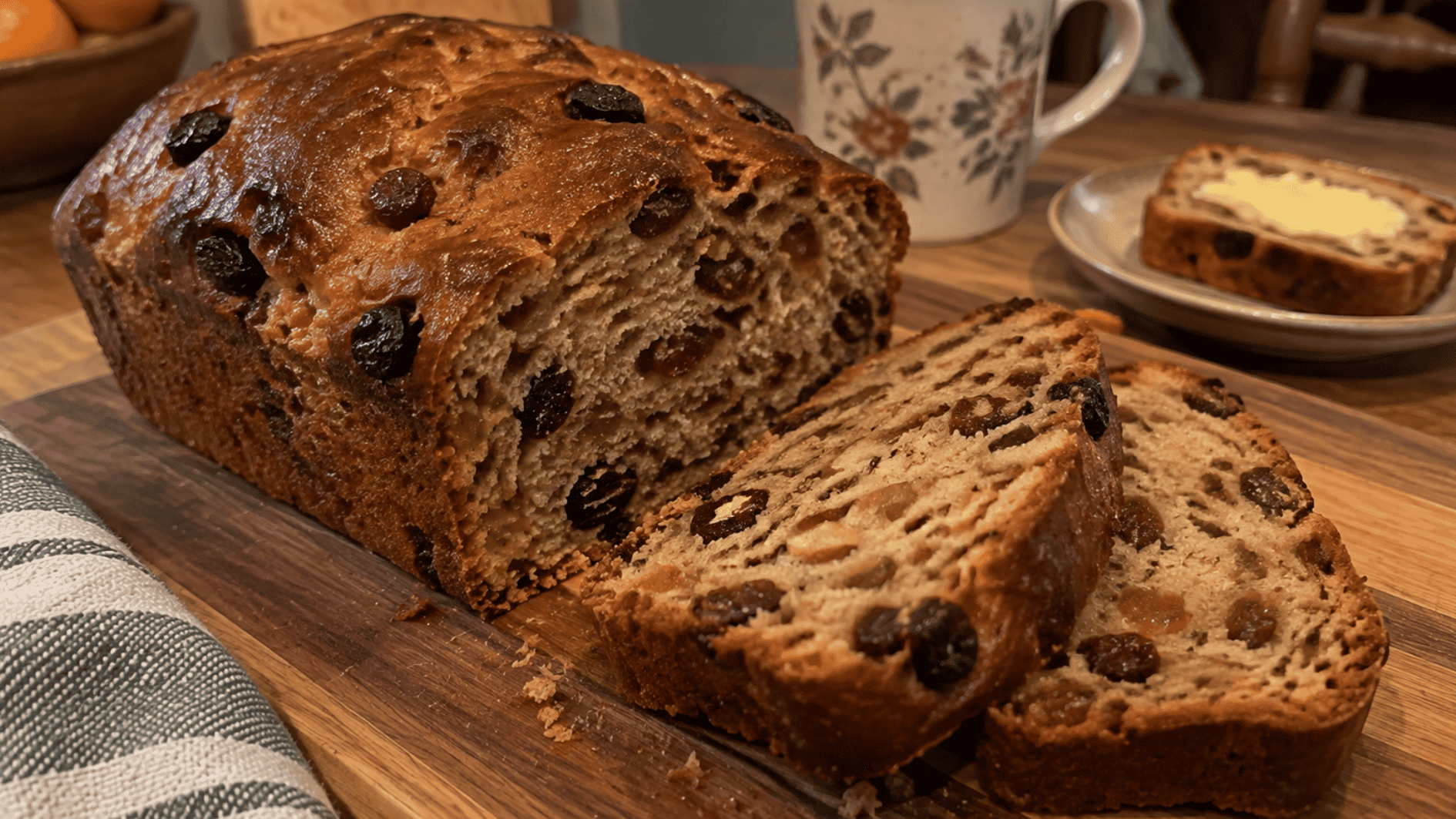traditional barmbrack fruit bread with raisins sliced on a wooden board beside butter
