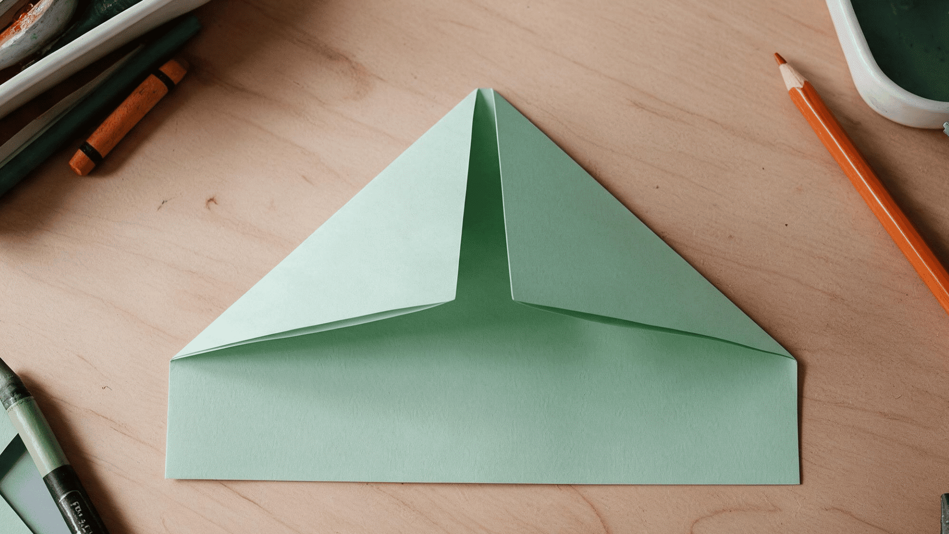 green paper folded into a triangle with corners meeting at center
