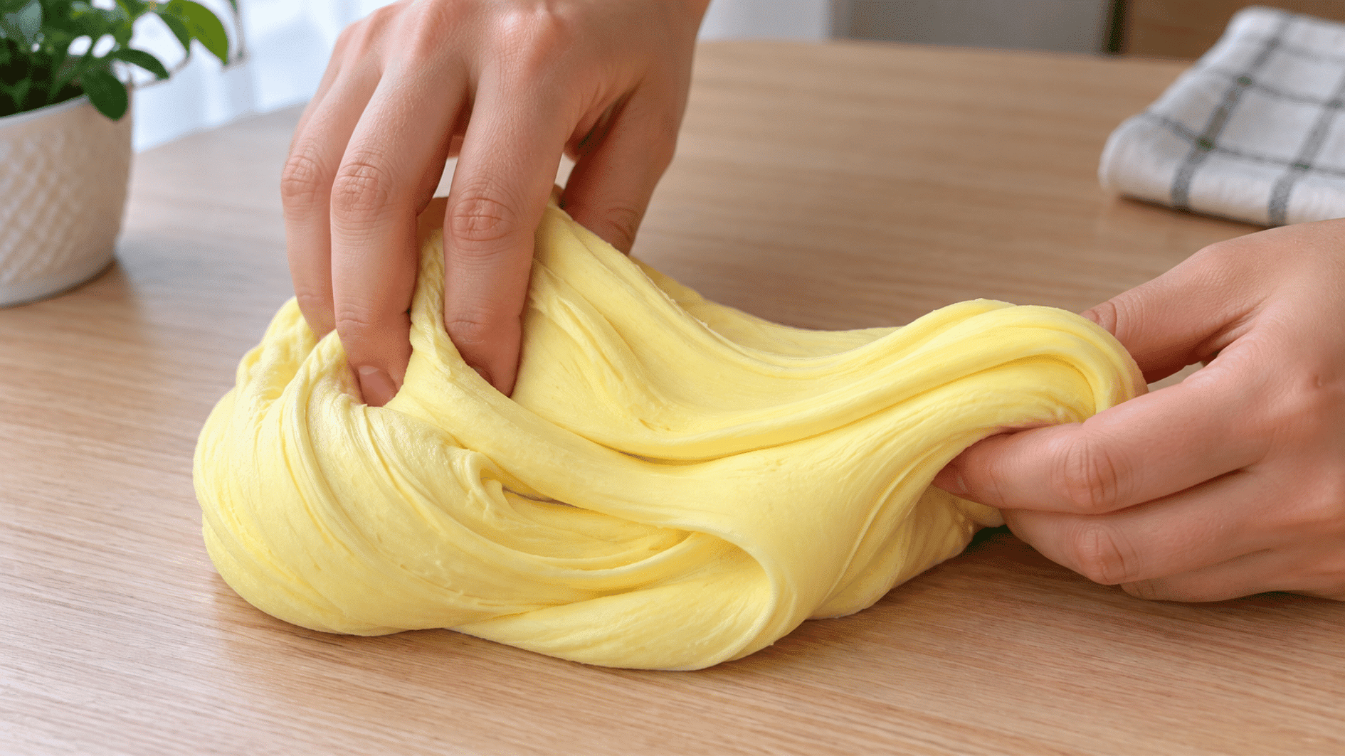 butter slime with a smooth soft clay-like texture spread inside a clear container on a wooden table