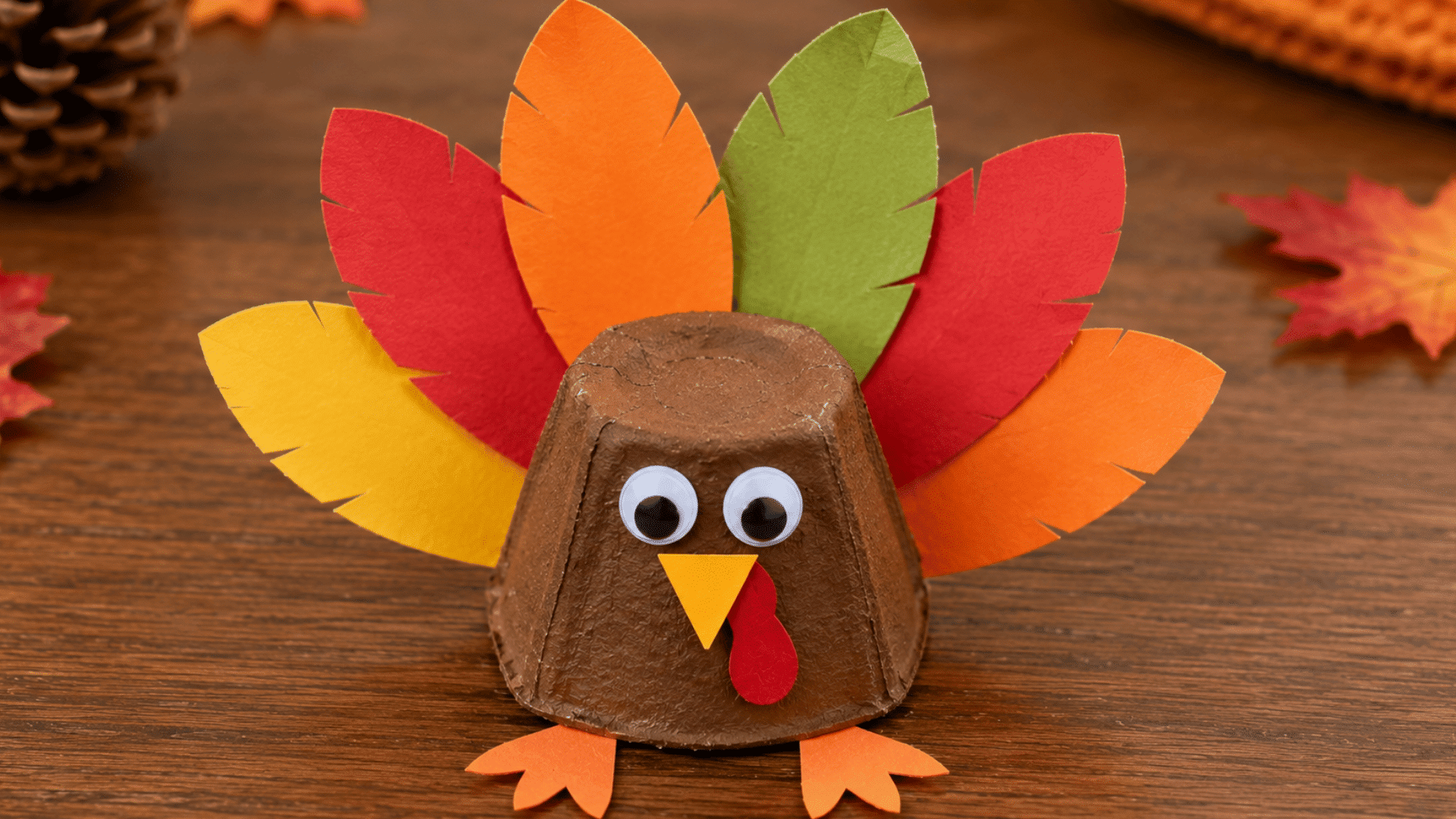 egg carton turkey craft with colorful paper feathers, googly eyes, beak, wattle, and small feet