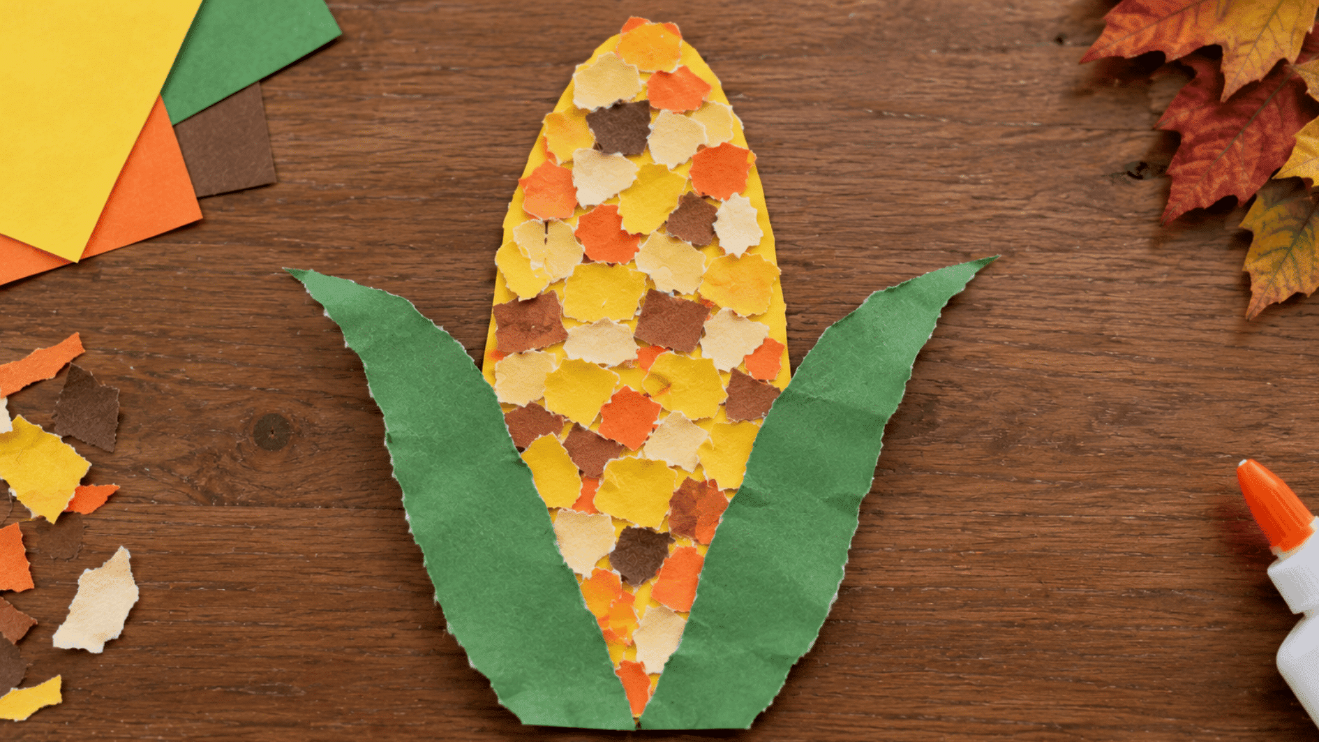 paper corn craft with torn yellow orange cream and brown kernels framed by green paper husks