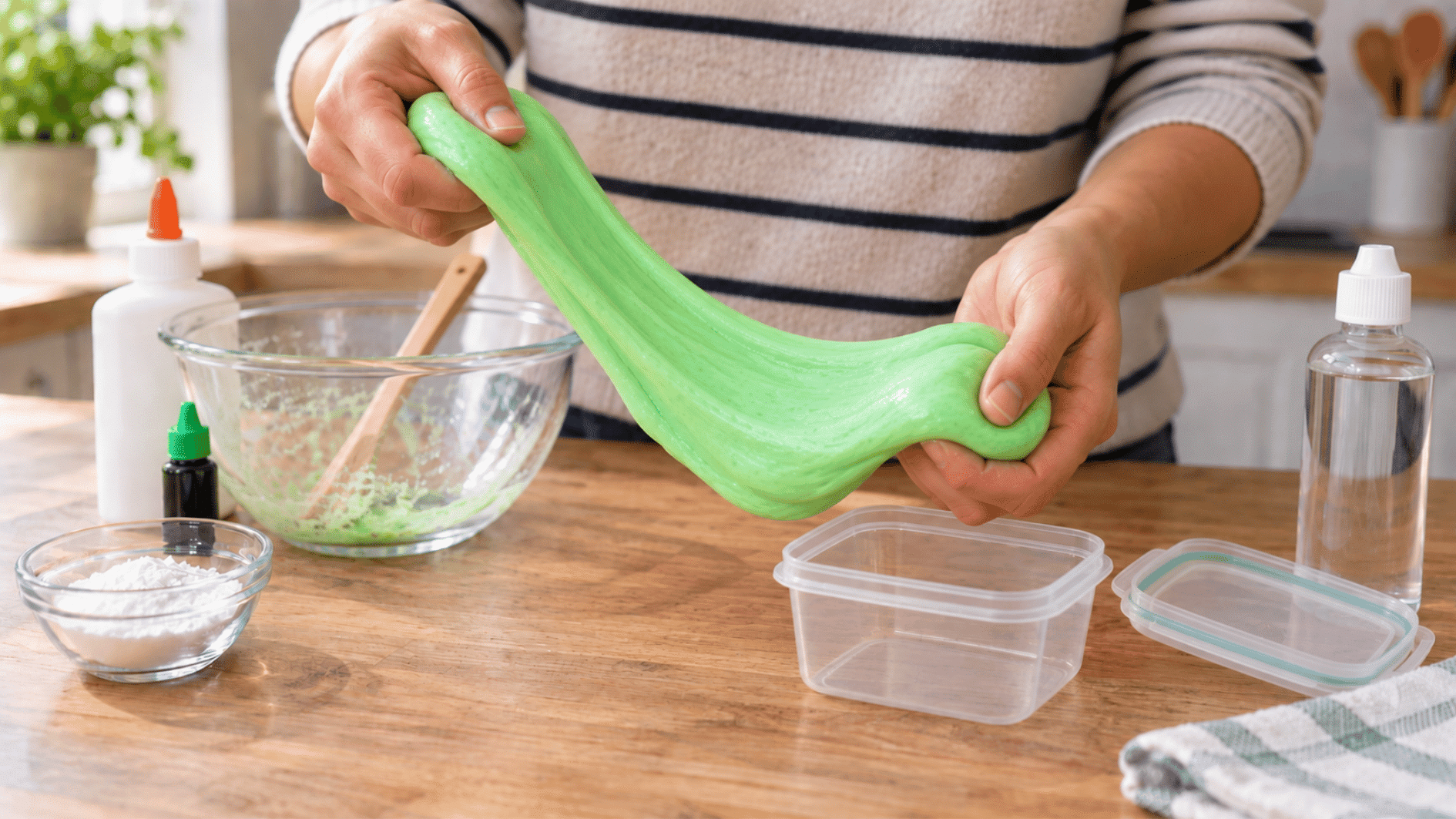 hands gently kneading soft green homemade slime until the texture becomes smooth and stretchy