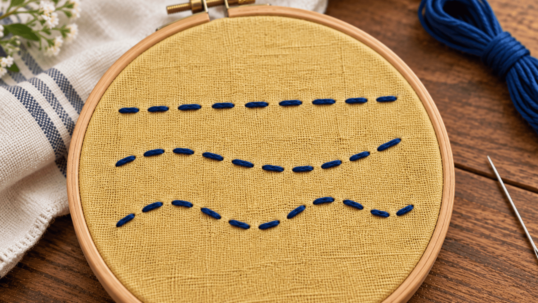 navy running stitch embroidery on mustard linen with clear dashed rows and even spaces between stitches