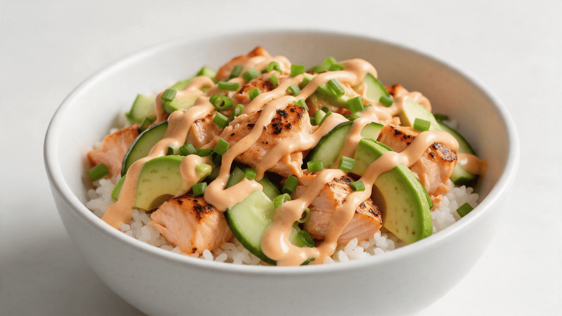 spicy salmon rice bowl with avocado cucumber green onions and spicy mayo