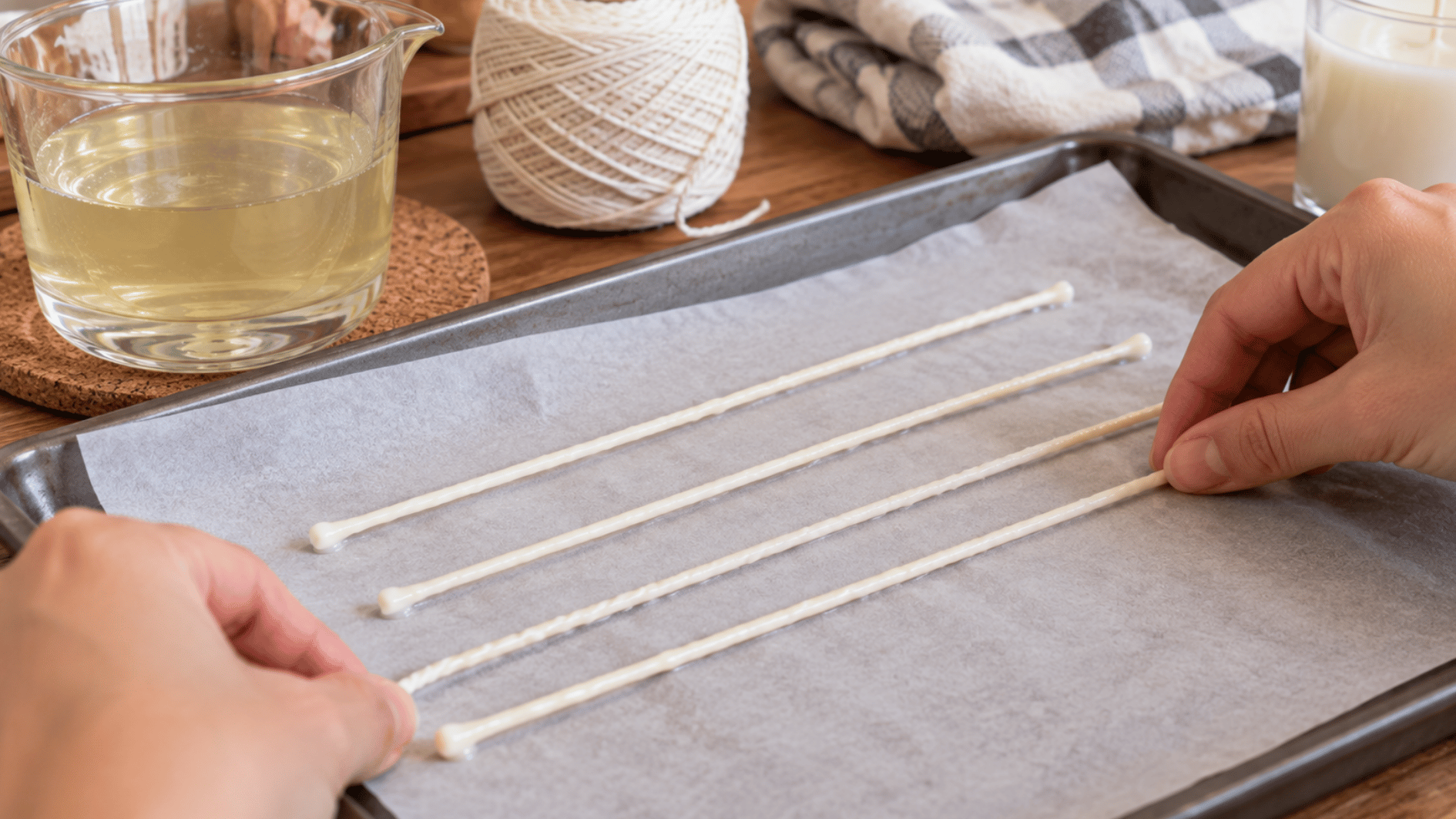 wax coated cotton candle wicks laid straight on parchment paper while cooling and hardening