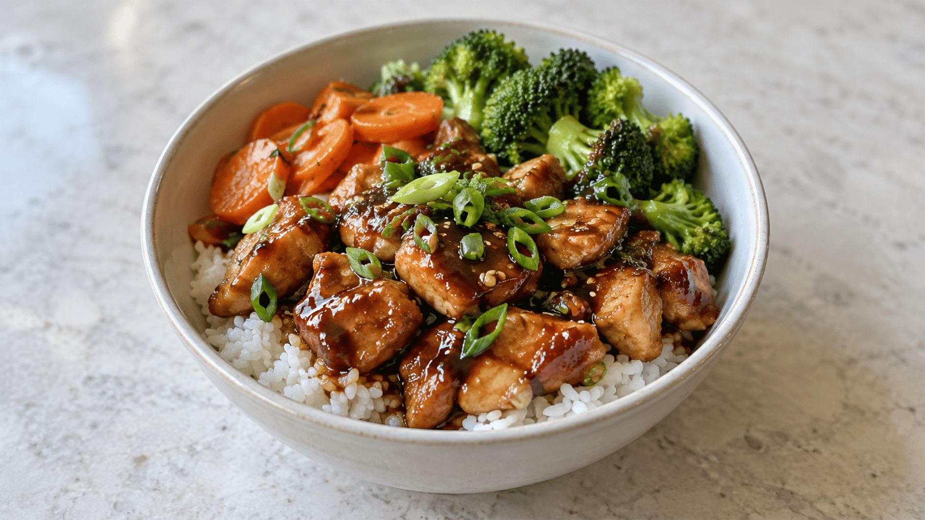 teriyaki chicken rice bowl with glazed chicken, rice, broccoli, carrots, and green onions