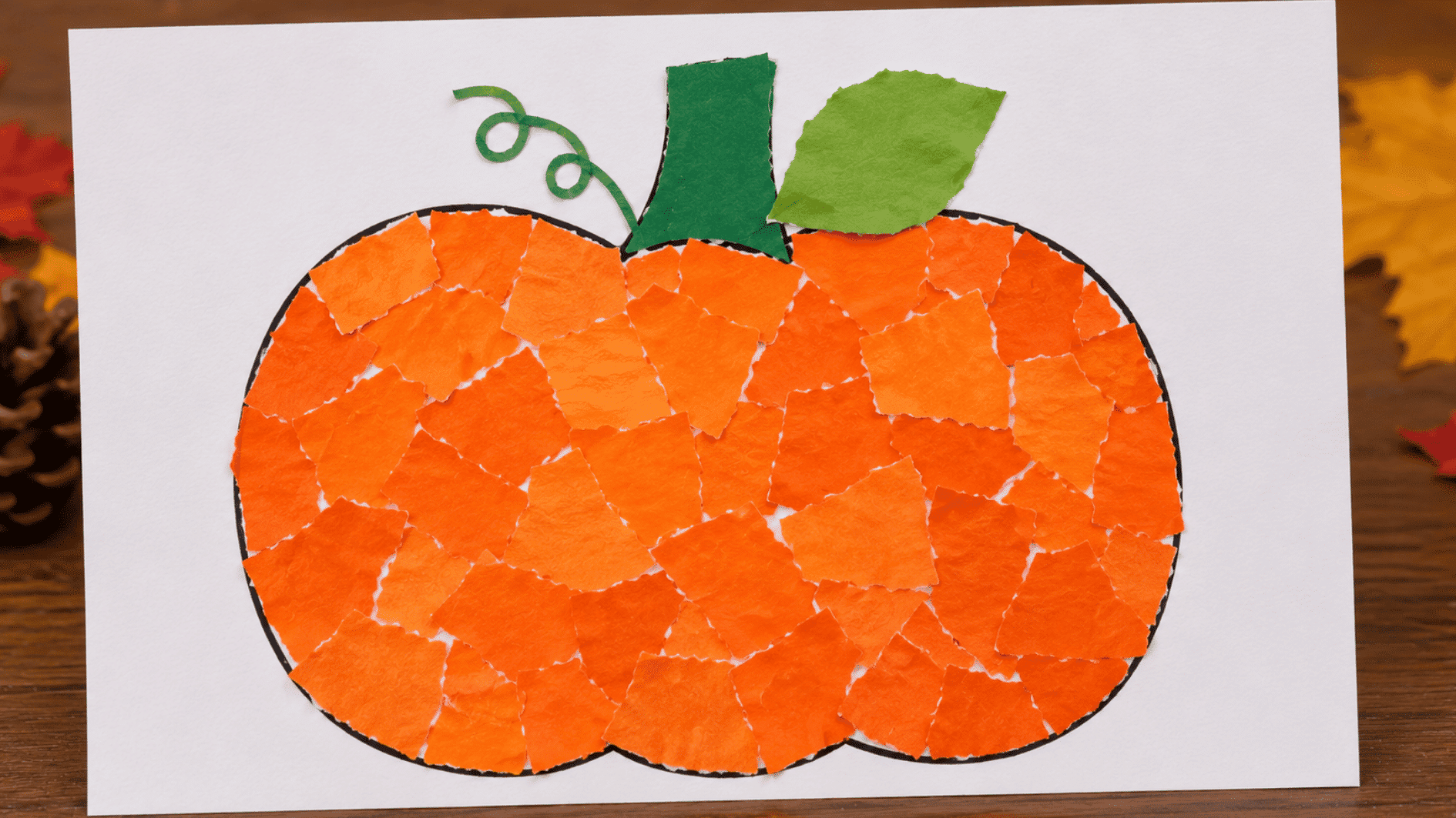 torn orange paper pumpkin collage with layered scraps, green stem, and leaf on white cardstocktorn orange paper pumpkin collage with layered scraps, green stem, and leaf on white cardstock