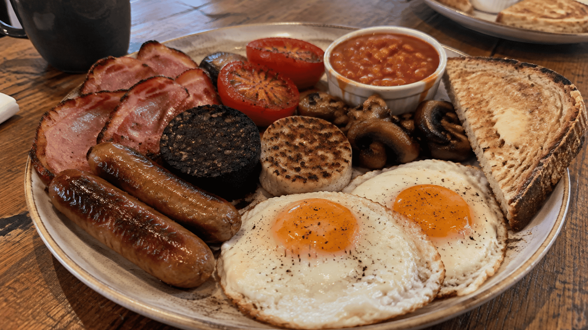 traditional irish breakfast with eggs sausages bacon mushrooms tomatoes beans and toast on a plate