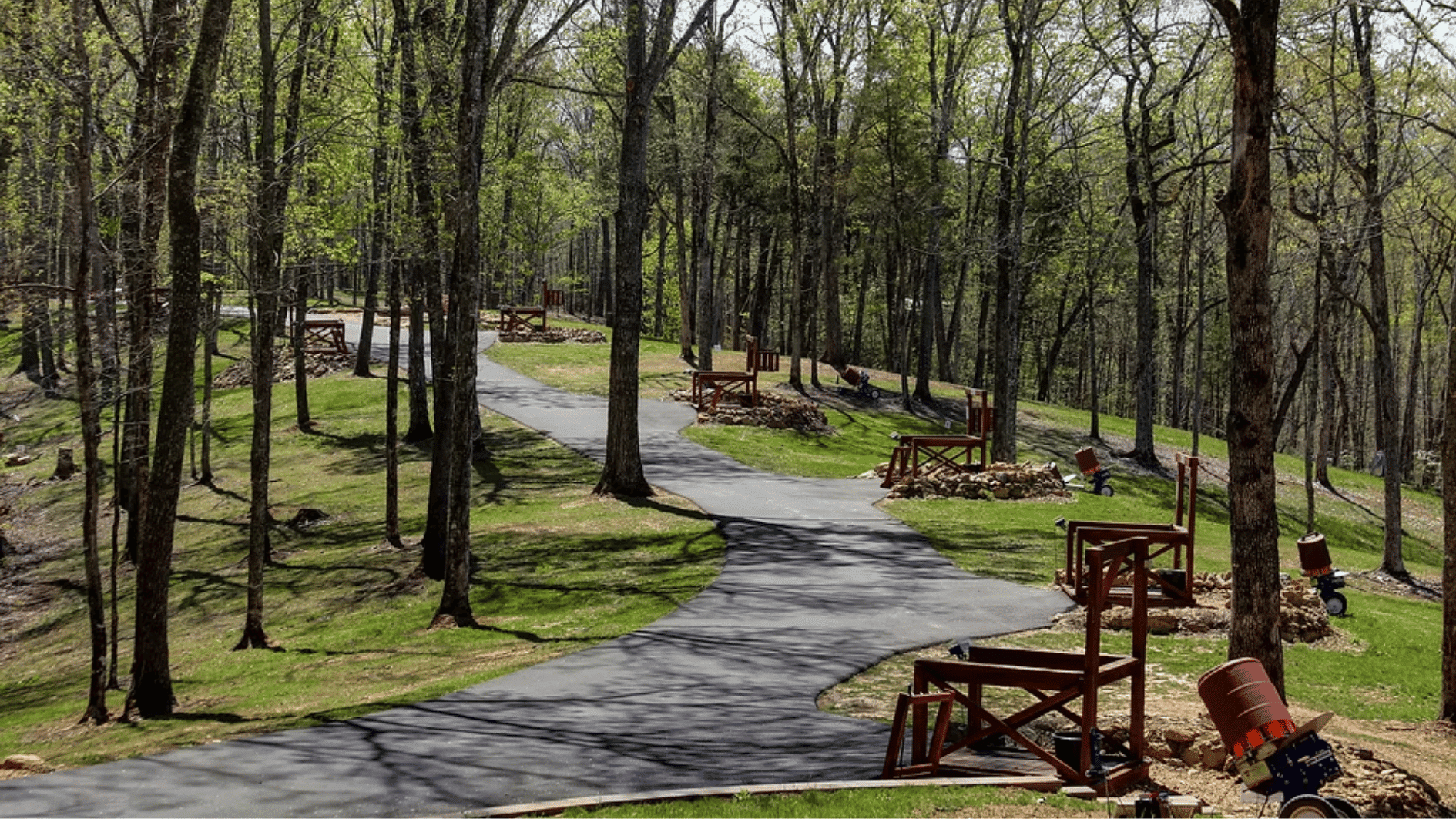 wooded outdoor shooting range with paved paths, target stations, and trees surrounding the practice area